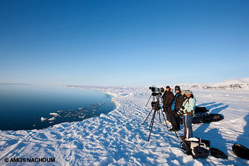 Guests of Amos Nachoums expedition line the floe edge in anticipation of narwhals and polar bears.