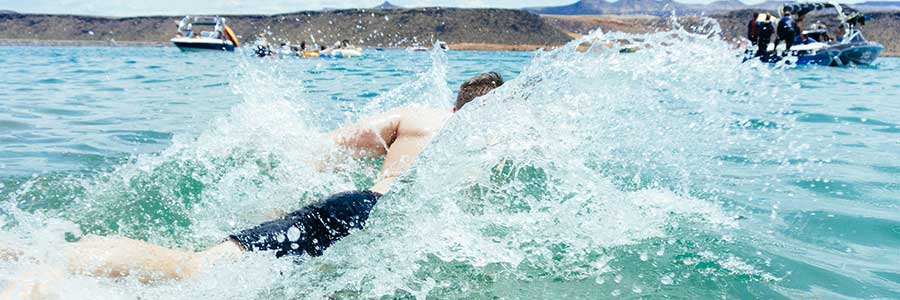 young man swims toward boat