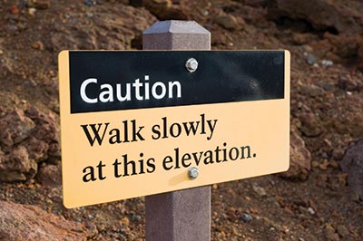 trail sign warns hikers to walk slowly at high elevation