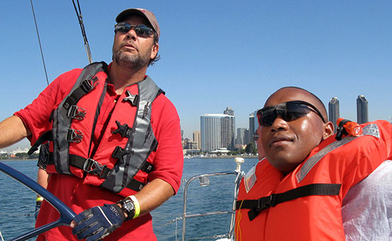 volunteer from Challenged America teaches a marine how to adjust sails on a sailboat