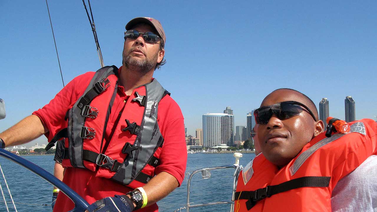 volunteer captain teaches marine how to adjust the sails