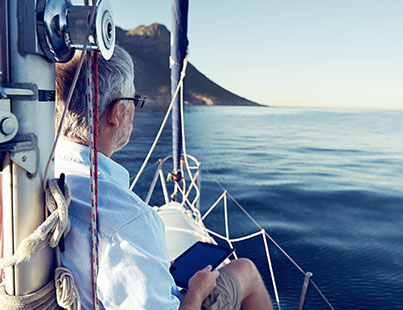 mature man reading a tablet on the bow of a boat