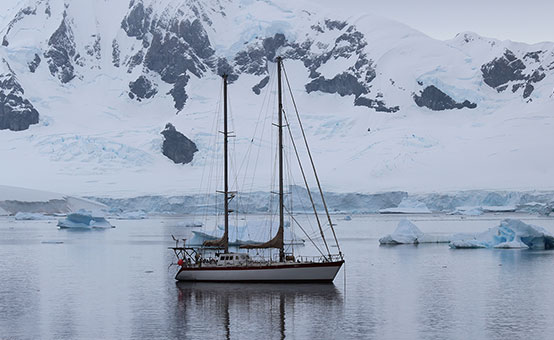 sailboat cruising by icebergs