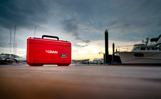 DAN first aid kit sitting on marina boat dock at sunrise