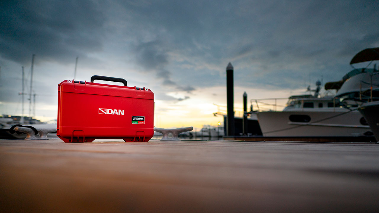 DAN first aid kit sitting on a marina boat dock at sunset