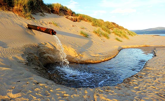 pipe pumps waste water onto the beach