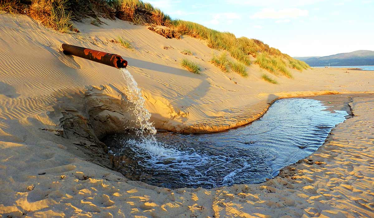 pipe pumps waste water onto the beach