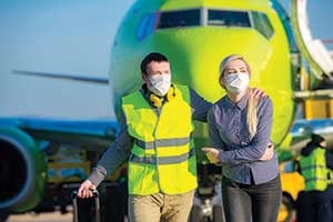 airport personnel escort sick patient wearing a facemask