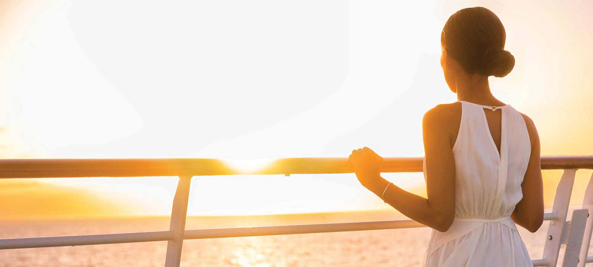 woman on a boat looking at the horizon at sunset